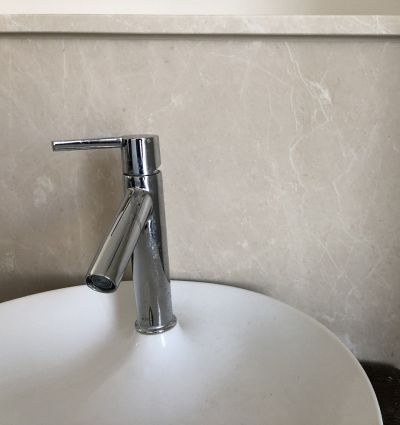 Steinückwand beige mit Waschschüssel im Bad