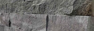 Schwarze Basalt Natursteinmauer mit spaltrauer und getrommelter Oberfläche