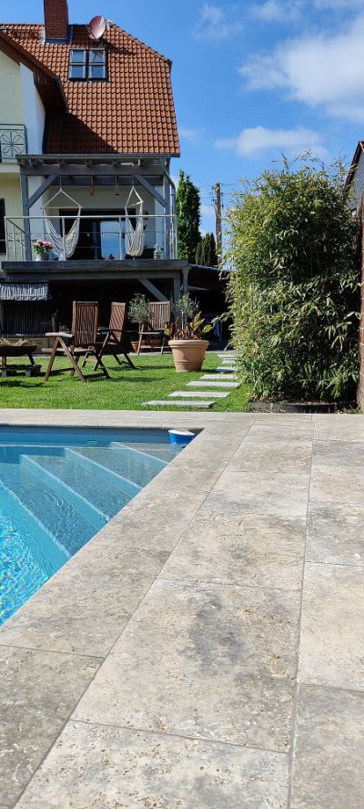 schöner Pool im Garten mit beige-grauen Travertin Silver Natursteinplatten